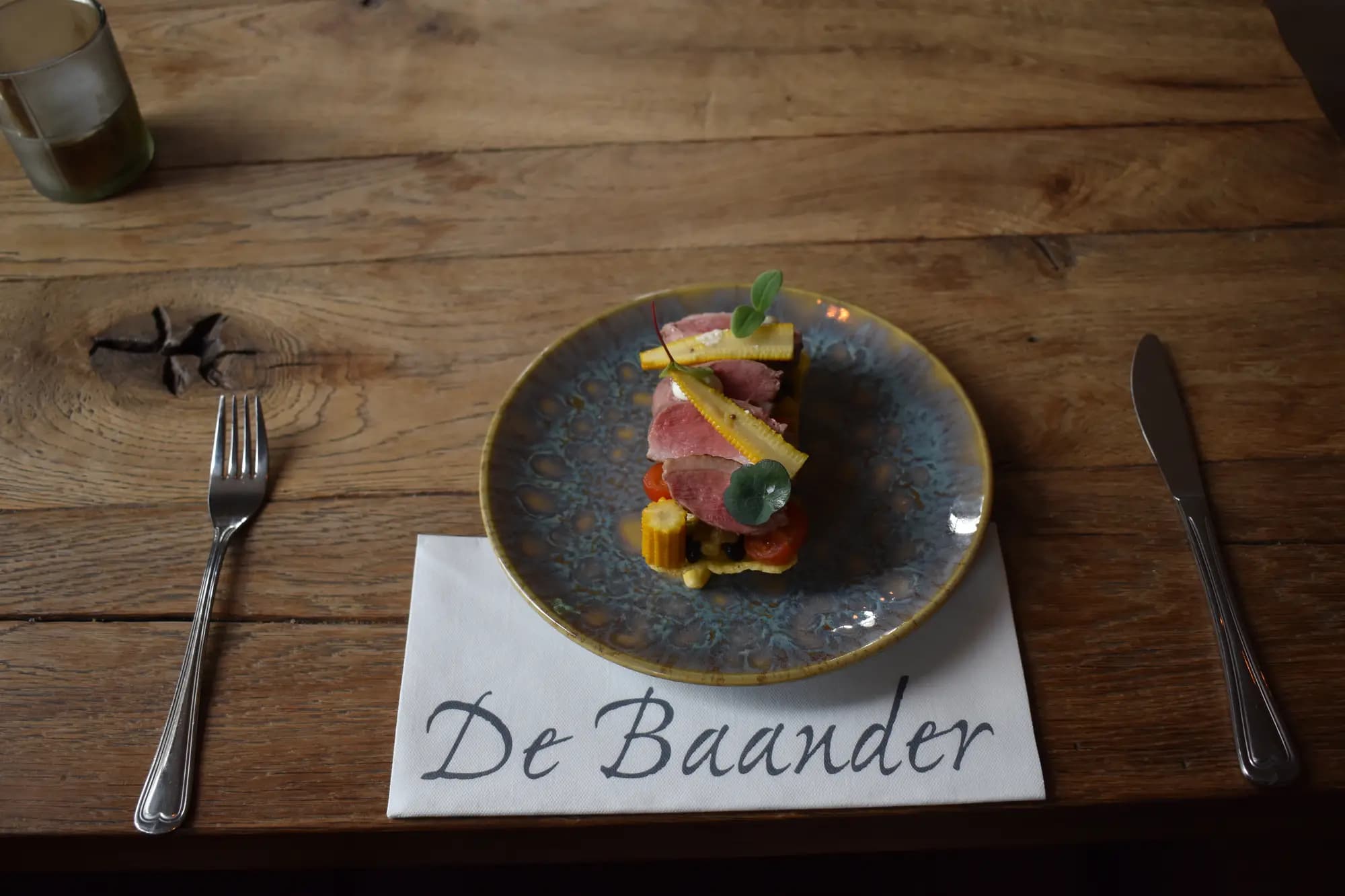 Voorgerecht met rosé vlees en groenten op keramisch bord, met servet van De Baander