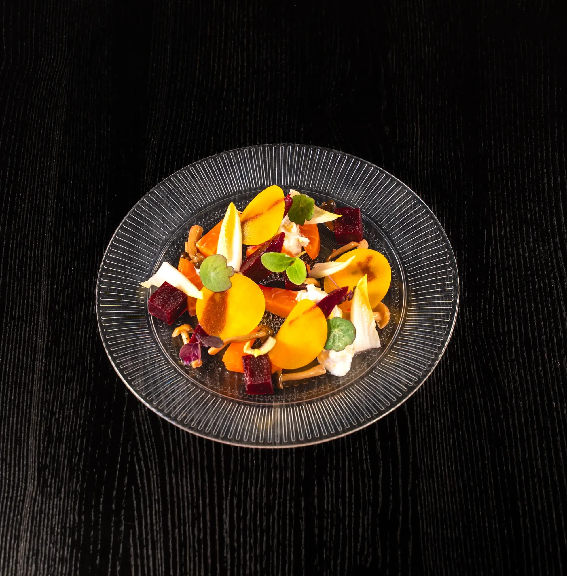 Salade van gele en rode biet met wortel, witlof en tuinkers op een glazen bord
