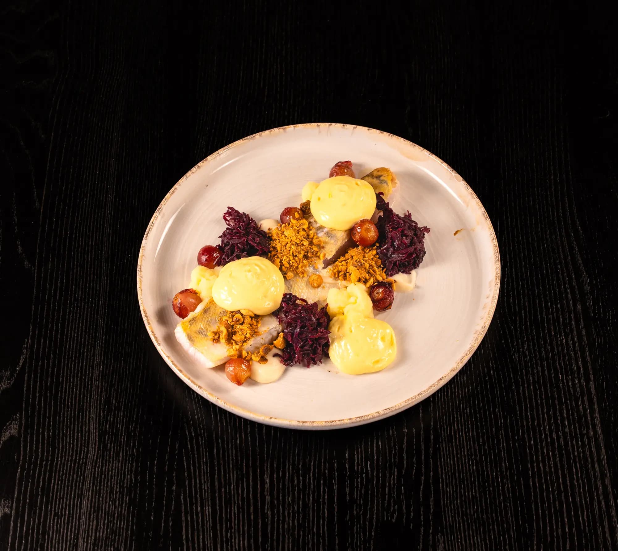 Gebakken visfilet met rodekool, druiven en saffraankleurige mayonaise op een wit bord