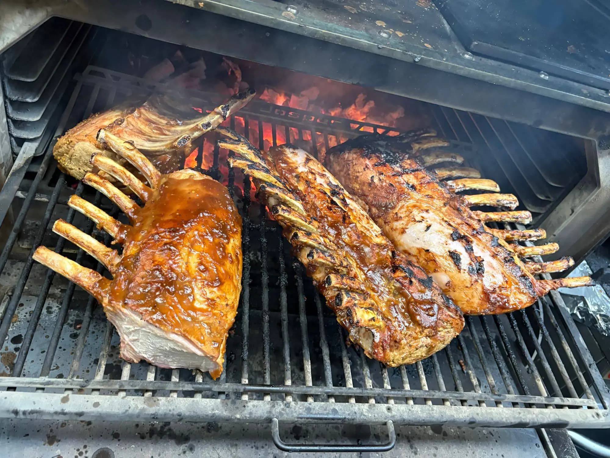 Gelakte lamsracks garen boven open vuur op een grill tijdens een cateringopdracht