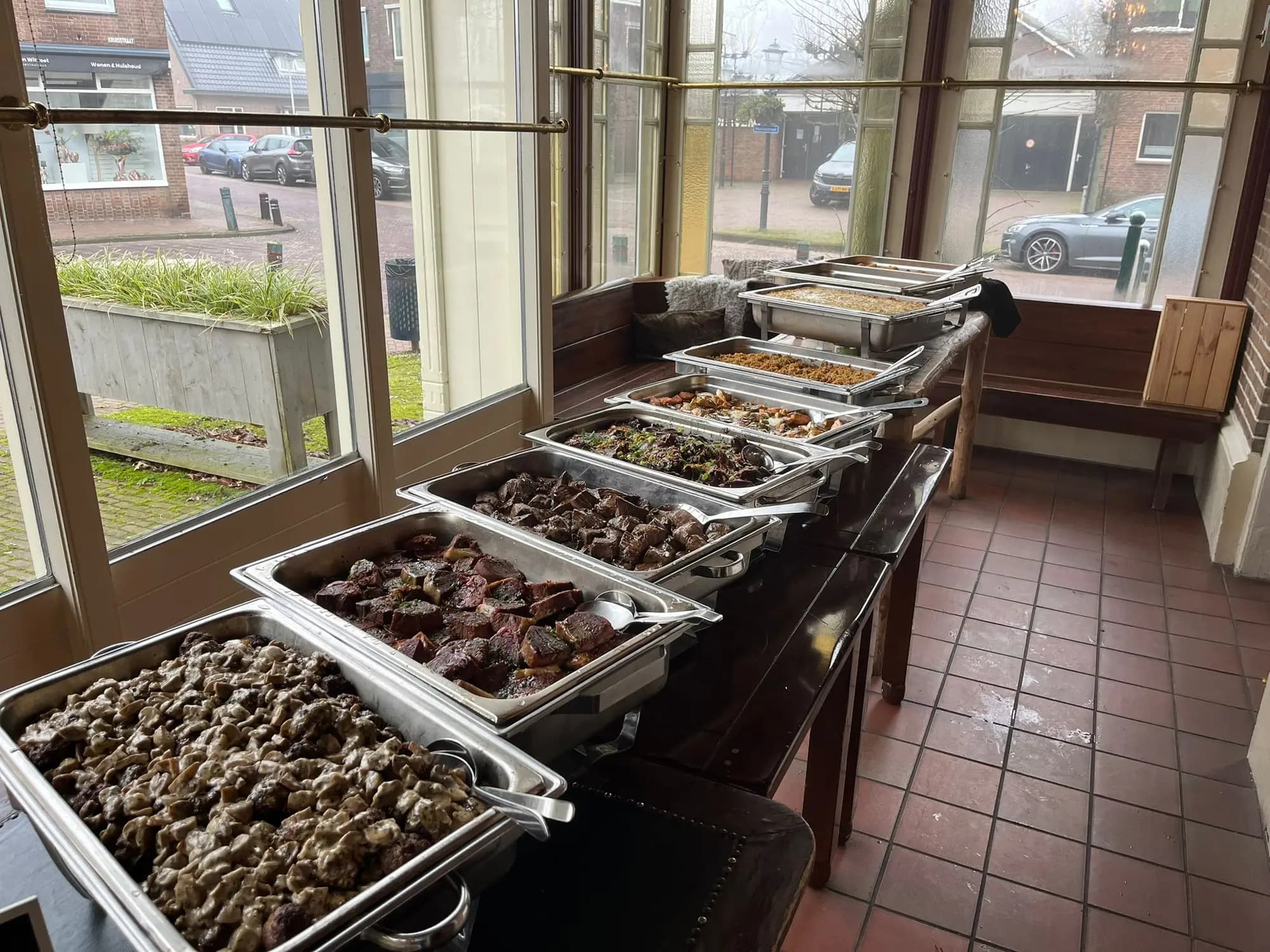 Rij chafing dishes met warme vleesgerechten en rijst op een buffet in de serre