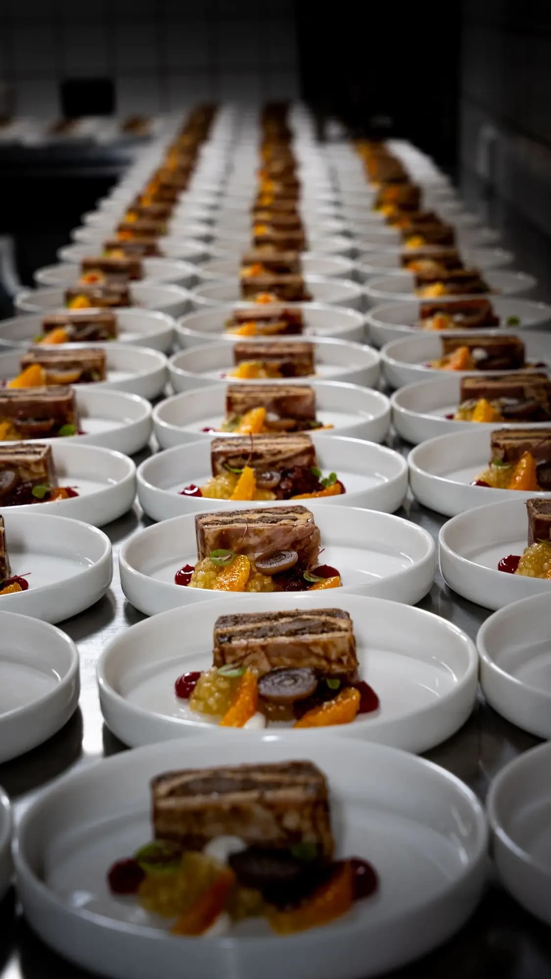 Terrine met compote en garnituur, uitgeserveerd op tientallen borden in de keuken