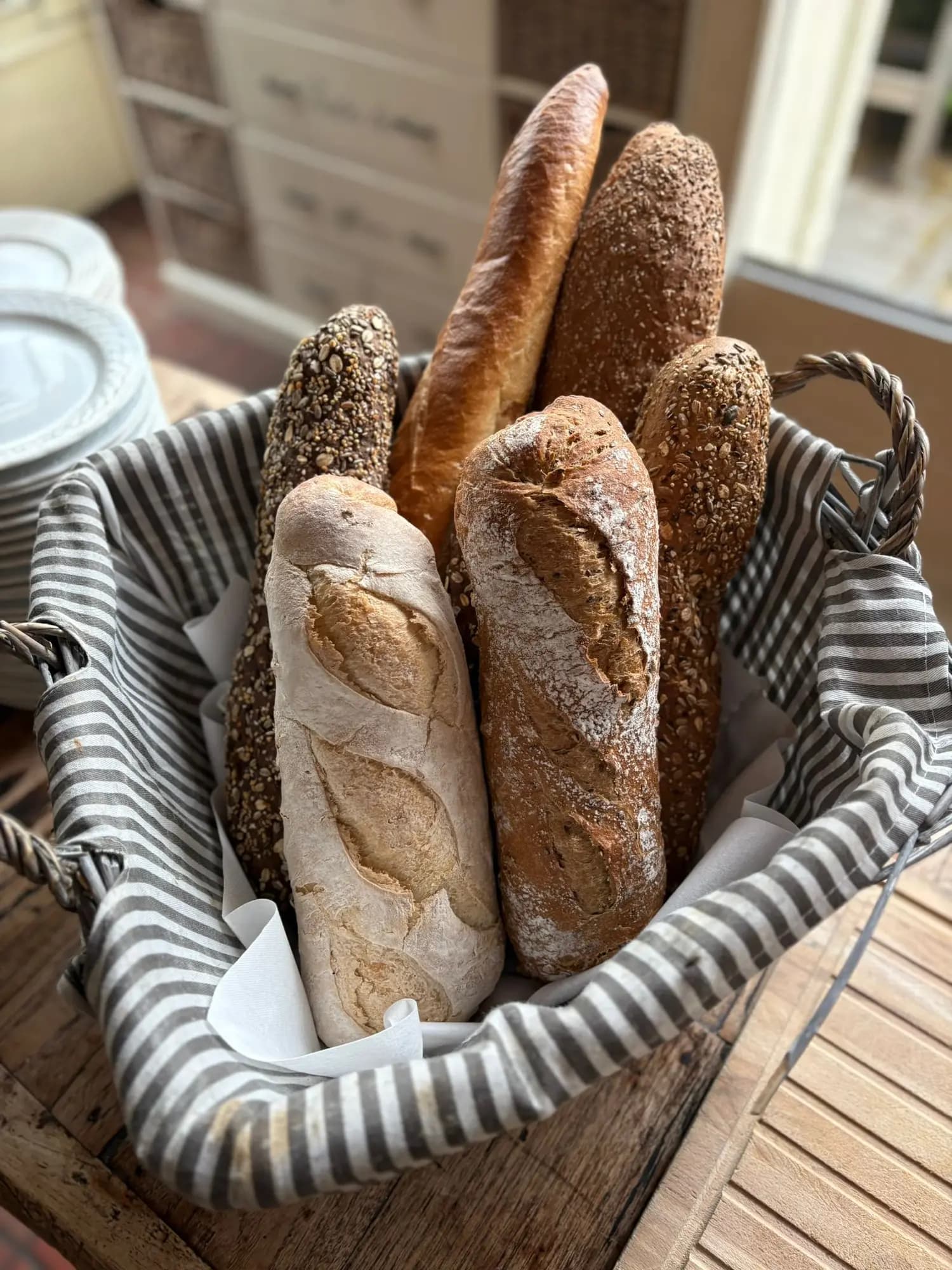 Verschillende soorten vers stokbrood in een rieten mand met gestreepte doek