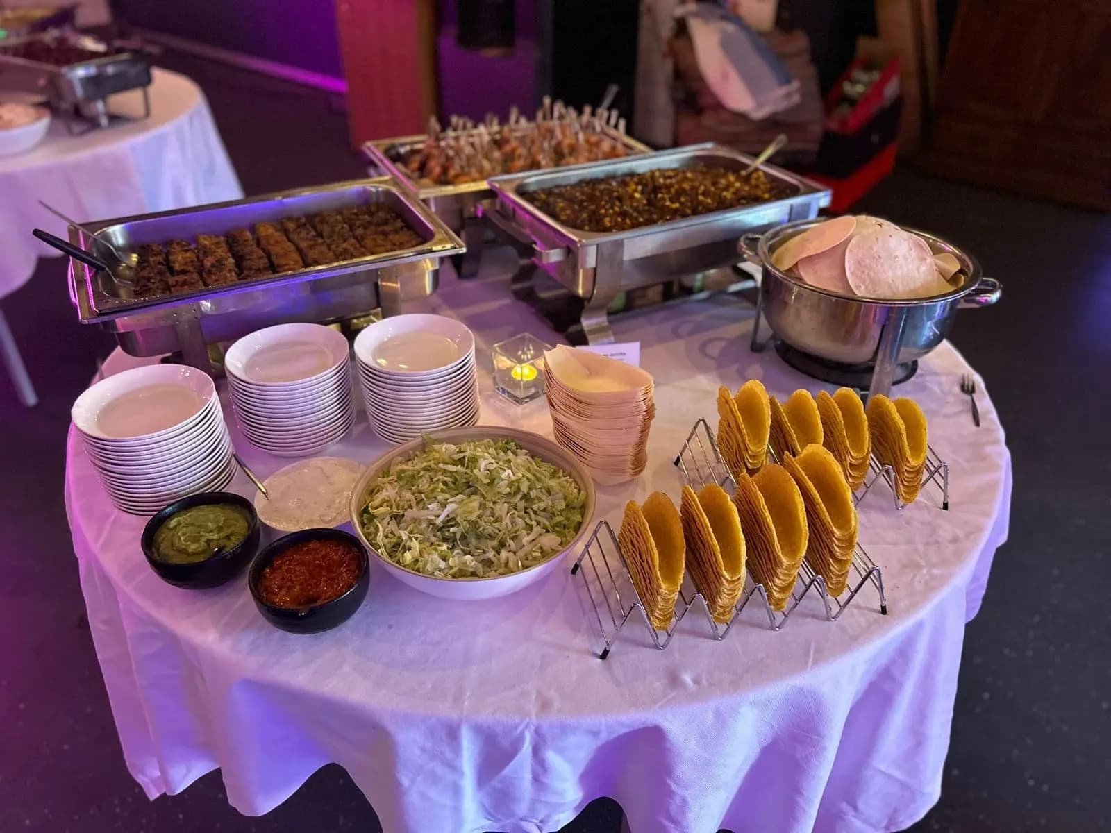 Buffet met satéspiesjes, taco's, guacamole en salsa in chafing dishes op een ronde tafel