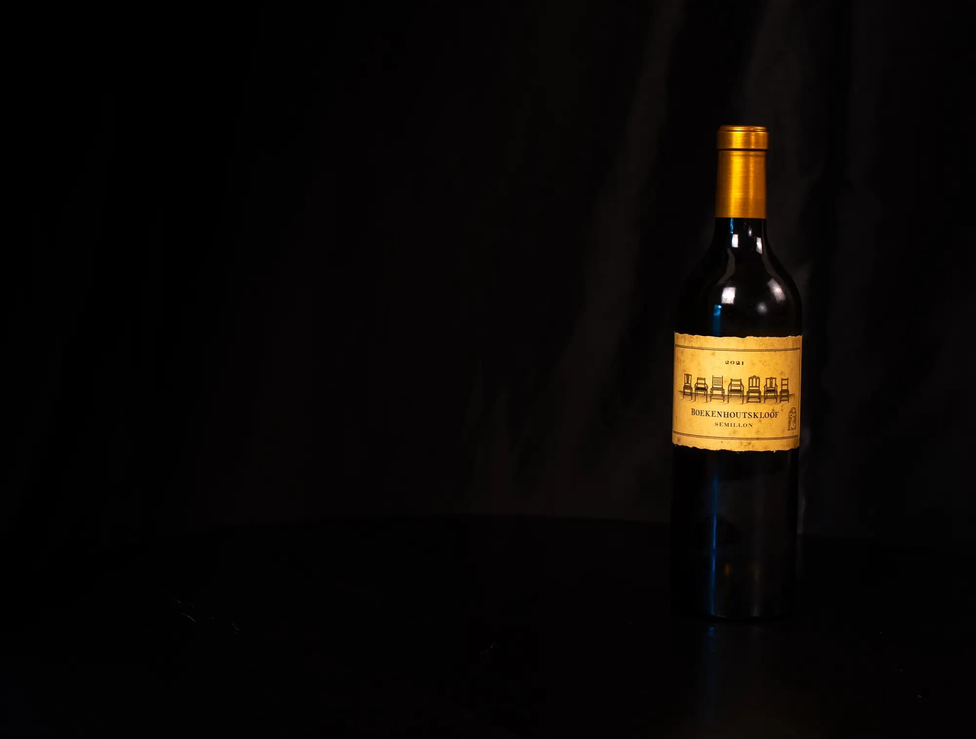 Fles Boekenhoutskloof Semillon met goudkleurige capsule, uitgelicht tegen zwarte achtergrond